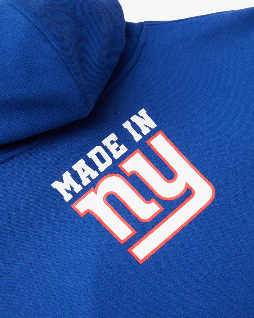 An angled artisitc photo of the rear of a Blue Hoodie, featuring the text Made in NY using the OFFICIAL NFL GIANTS Jersey Font.