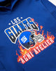 An angled artistic shot of a Blue Hoodie with Los GIANTS emblazoned upon it, featuring a graphic of the NY GIANTS NFL FOOTBALL TEAM HELMET and the Agni Atelier logo in the foreground, with flames in the background