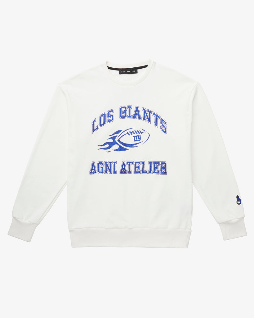 A White Crew Neck with Los GIANTS on it, featuring a graphic of a football on fire with NY GIANTS and the Agni Atelier logo. The Text and graphics all have a shimmering blue color.